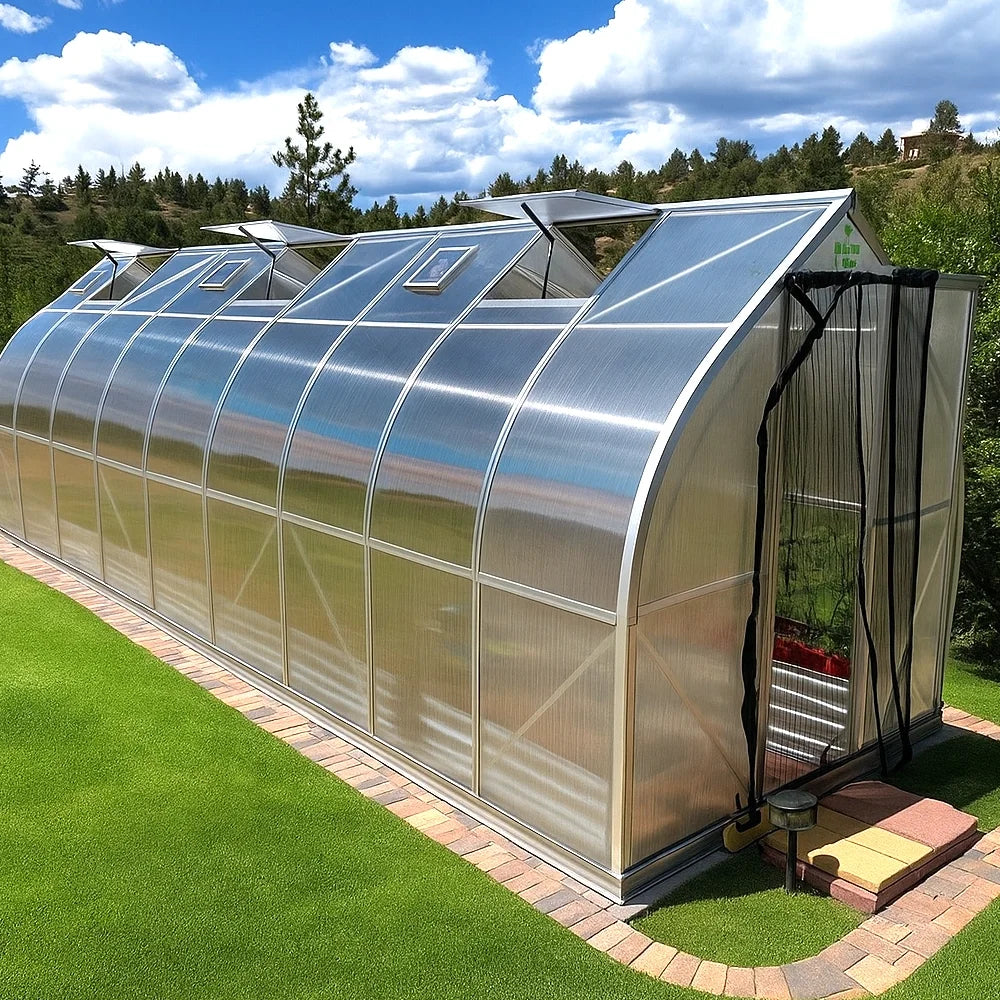 Gotic arch polycarbonate greenhouse 7x21 on a grassy area with trees in the background.