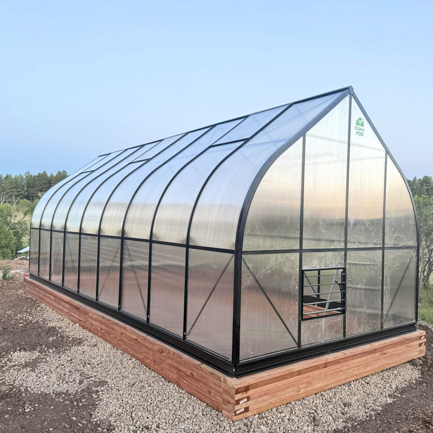 Heavy Duty Polycarbonate greenhouse with wooden foundation on a clear day