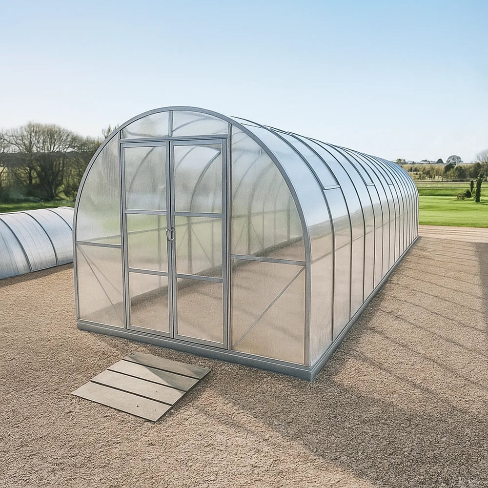 9x35 Greenhouse with a clear polycarbonate roof and walls on a gravel surface with grass and trees in the background.