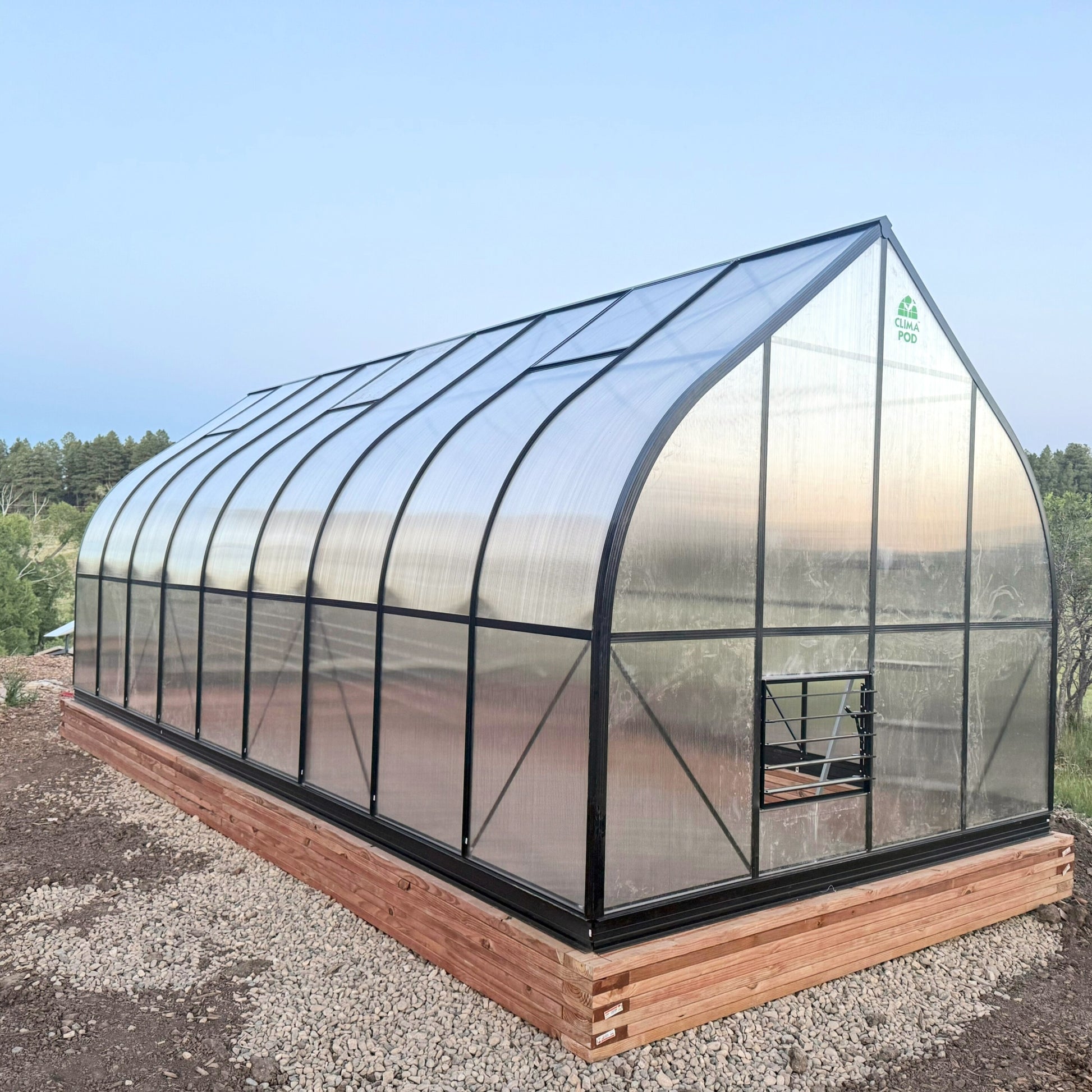 Heavy Duty Polycarbonate greenhouse with wooden foundation on a clear day