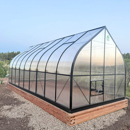 Heavy Duty Polycarbonate greenhouse with wooden foundation on a clear day